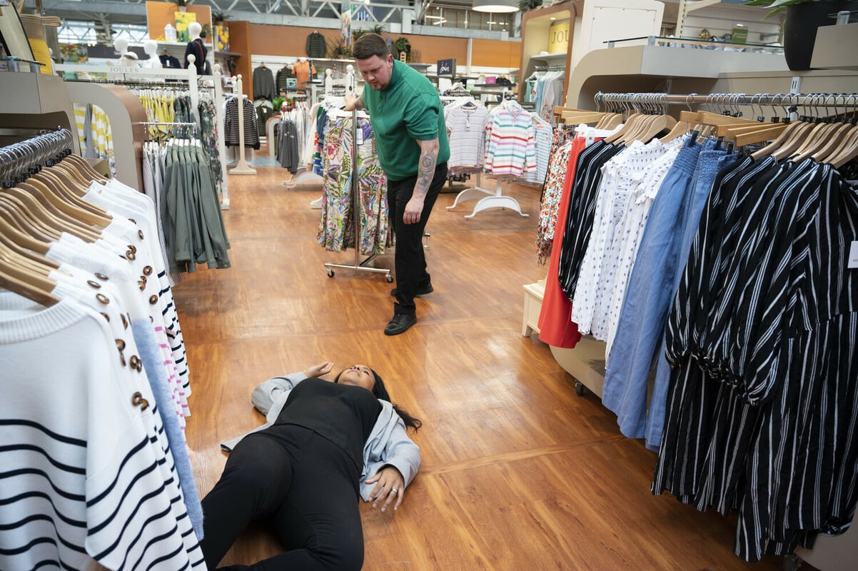Member of the public having a seizure in a store. A first aid trained member of staff is approaching them.