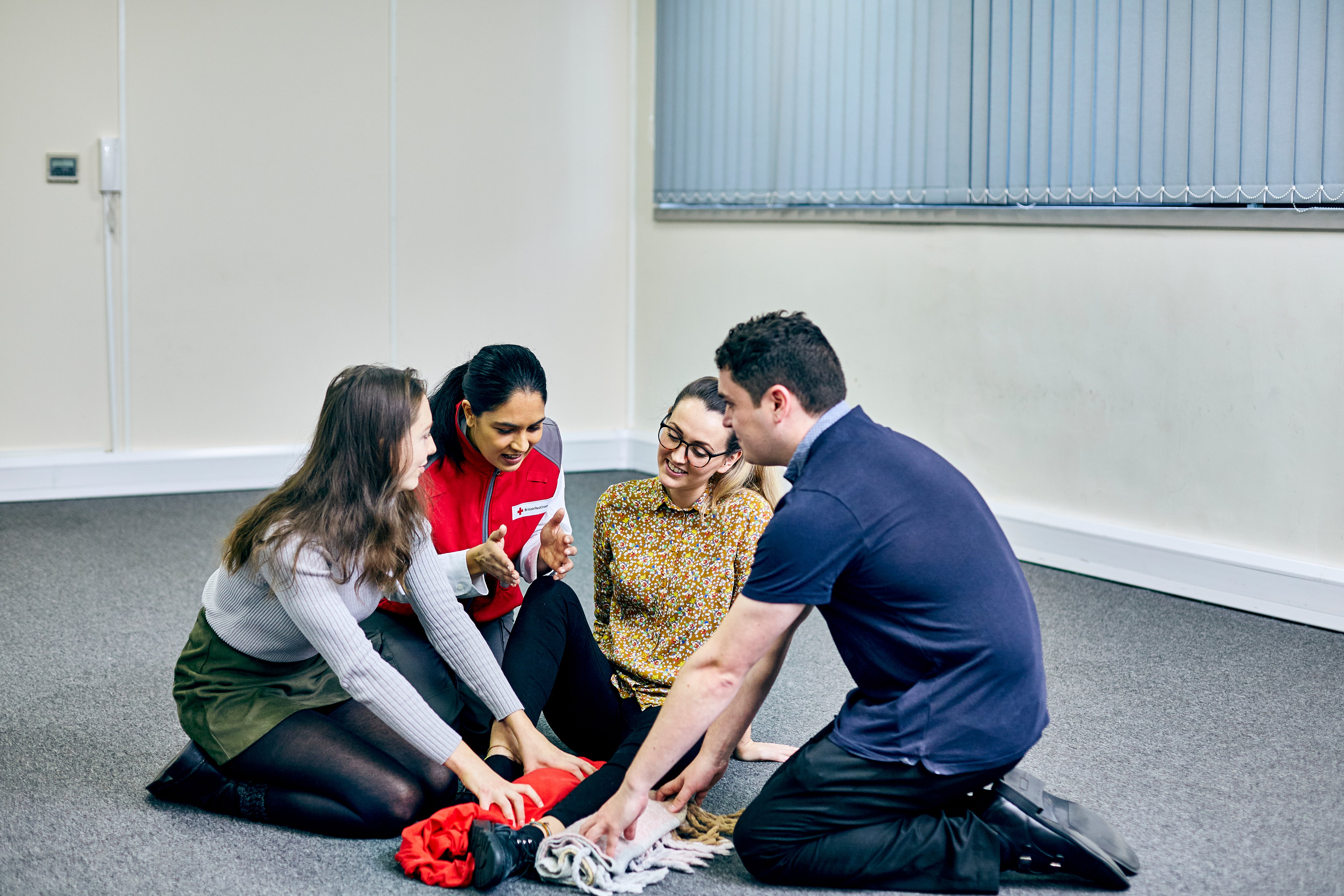 A British Red Cross trainer teaching a group how to react to someone with a knee injury